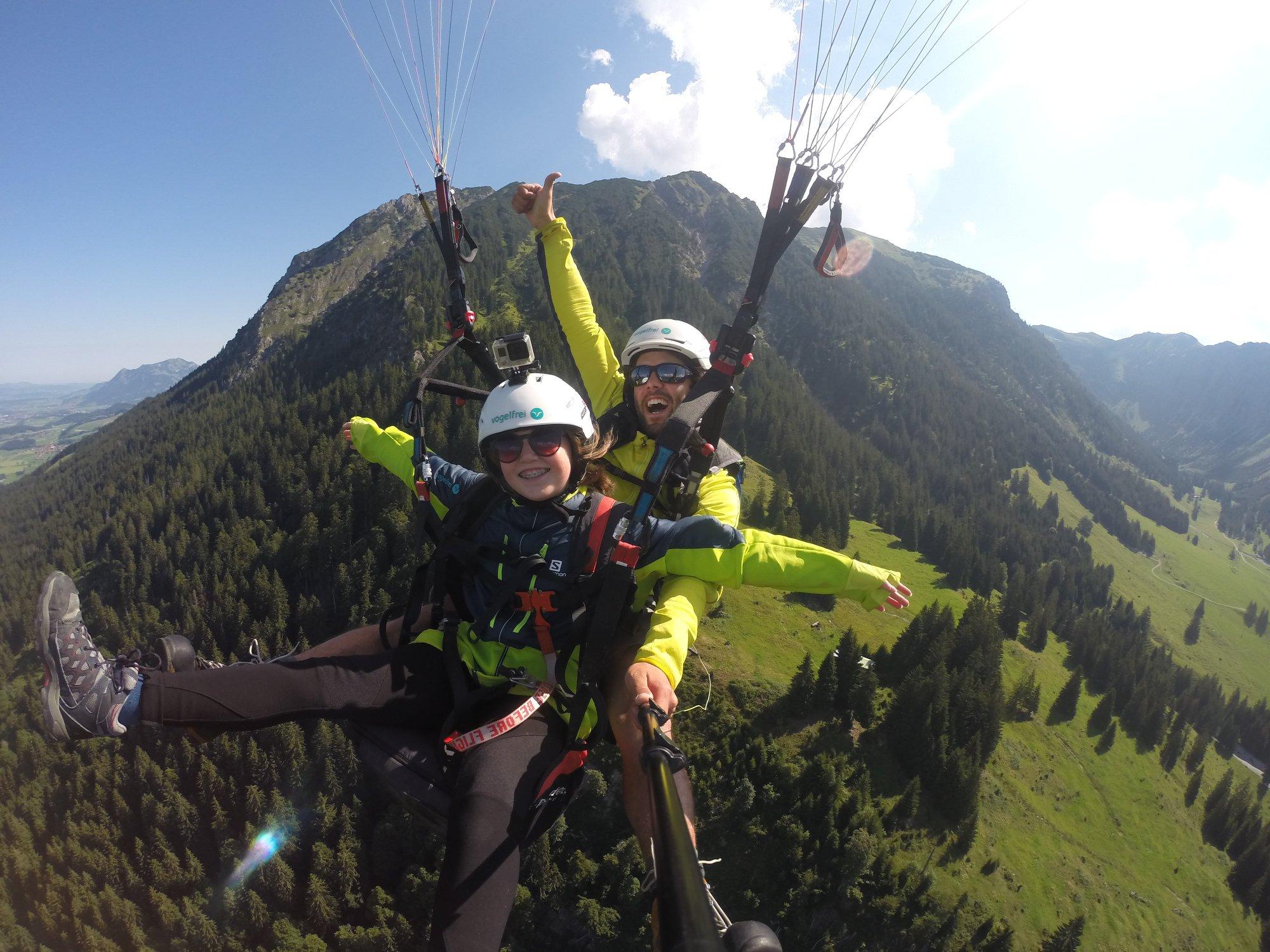 A woman flying during Tandem Paragliding at Mittagbahn - Panorama Flight with vogelfrei Allgäu.
