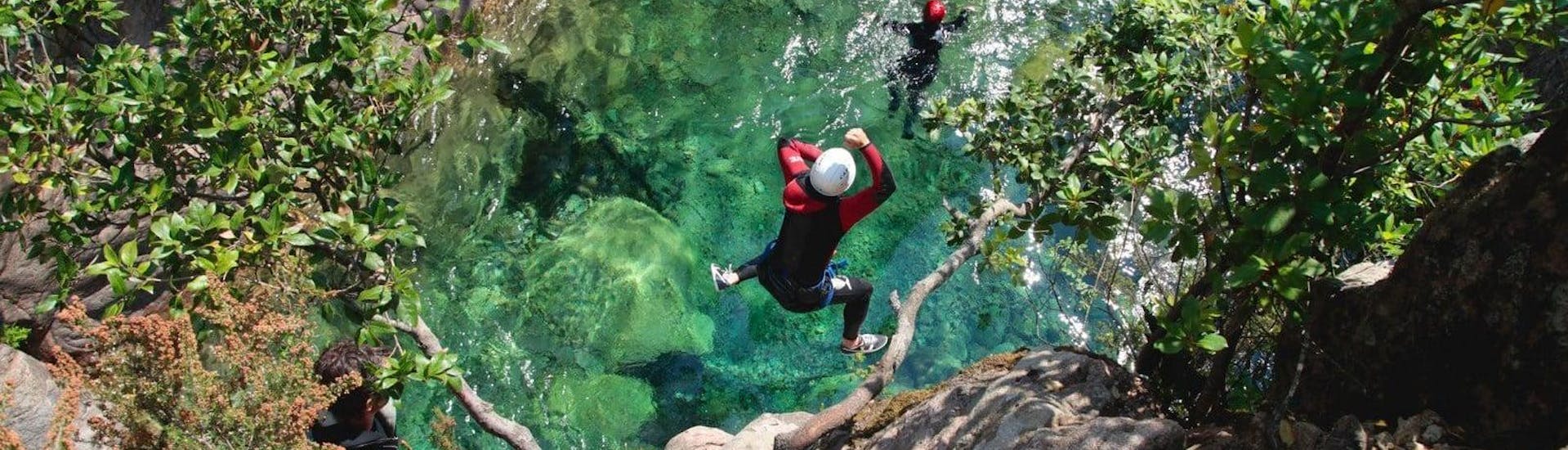 Ein Teilnehmer des Canyoning im Pulischellu springt unter Aufsicht eines qualifizierten Canyoning-Guides von Acqua et Natura in einen smaragdgrünen Naturpool.