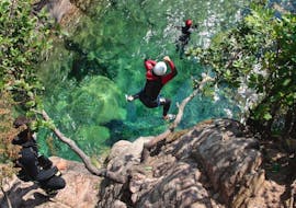 Pendant la sortie Canyoning "Sport" - Canyon de Purcaraccia, un amateur de canonyning saute dans une belle piscine naturelle depuis un rocher sous la supervision d'un guide de canyoning expérimenté d'Acqua et Natura.