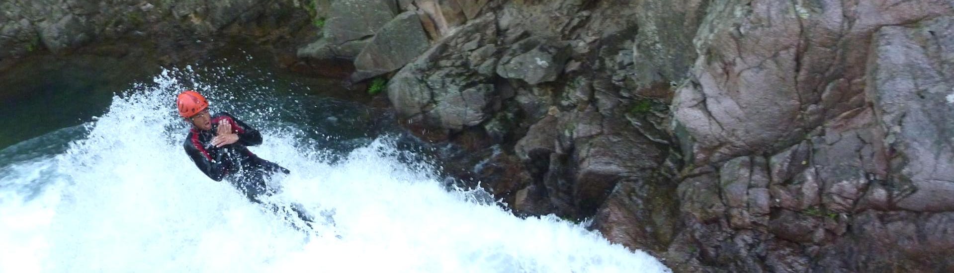 Ein Mann rutscht während des von Acqua et Natura organisierten Canyoning in der Purcaraccia-Schlucht eine natürliche Wasserrutsche hinunter.