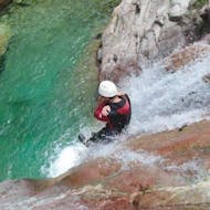 Een man glijdt van een zeer steile waterglijbaan tijdens de Canyoning "Sport & Aquatic" - Canyon de la Vacca georganiseerd door professionals van Acqua et Natura.