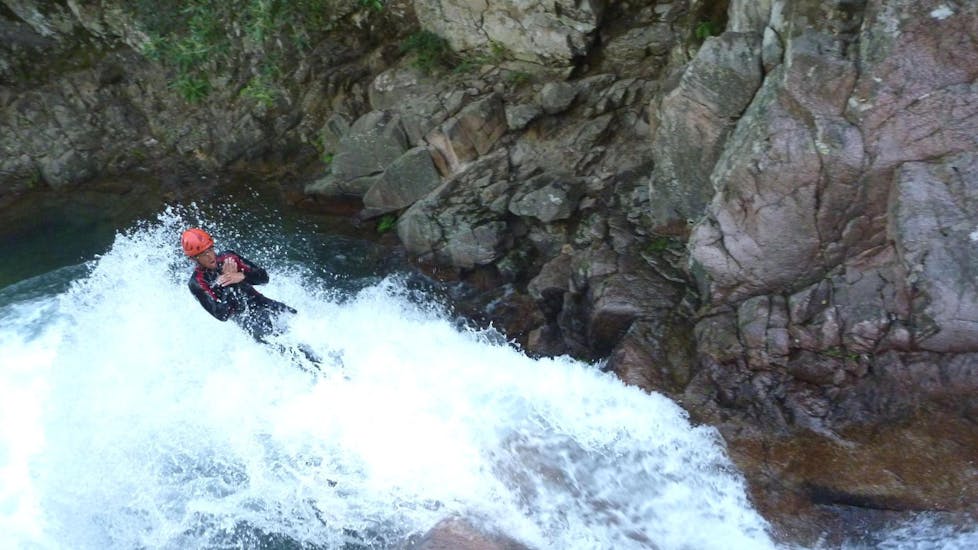 Un homme s'amuse à glisser sur un gigantesque toboggan naturel lors d'une sortie Canyoning "Aquatique" - Canyon de la Vacca organisée par les professionnels d'Acqua et Natura.