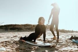 A girls is practicing her stands with an instructor in her private surfing lessons in Valencia with Anywhere Watersports.