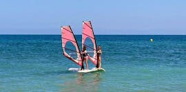 Zwei Frauen üben ihre Windsurfing-Fähigkeiten im Mittelmeer während ihres Windsurfing-Kurses für Anfänger in Valencia mit Anywhere Watersports.