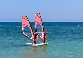 Two women are practicing their windsurfing skills in the Mediterranean Sea during their windsurfing lessons for beginners in Valencia with Anywhere Watersports.