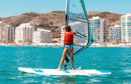 Una niña navega por las aguas del mar Mediterráneo durante su curso privado de windsurf en Valencia con Anywhere Watersports.