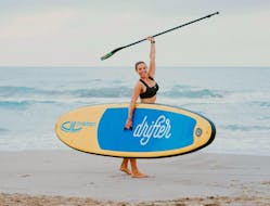 The woman is celebrating her success while punching her fist in the air during her private stand up paddleboarding lesson in Valencia with Anywhere Watersports.