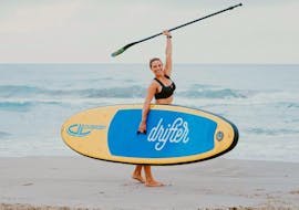 The woman is celebrating her success while punching her fist in the air during her private stand up paddleboarding lesson in Valencia with Anywhere Watersports.
