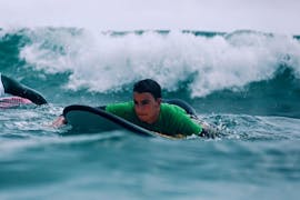 Ein Teilnehmer paddelt um eine Welle bei seinem Surfkurs in Cullera mit Anywhere Watersports zu erwischen. 