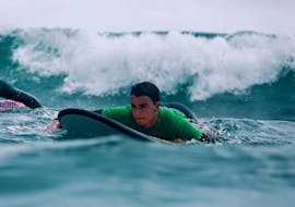 A participant is paddling his way down to catch a wave on his surfing lessons in Cullera with Anywhere Watersports. 