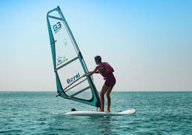 A man is standing up for the first time in the water with his windsurfing lessons in Cullera for beginners from Anywhere Watersports.