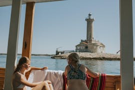 Deux filles profitent de la vue du phare lors de leur balade en bateau privé à Kamenjak avec le bateau de Rio Pula.