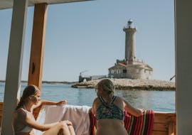 Two girls are enjoying the view of the lighthouse on their Private Boat Trip to Kamenjak with Rio Boat Pula.