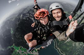 Een klant en de piloot lachen in de camera tijdens Tandem Paragliding over het Achenmeer - Boven de bergtoppen met Fly Achensee.