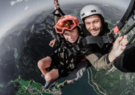 Eine Kundin und ein Pilot lächeln in die Kamera während des Tandem Paragliding über dem Achensee - Über den Gipfeln mit Fly Achensee