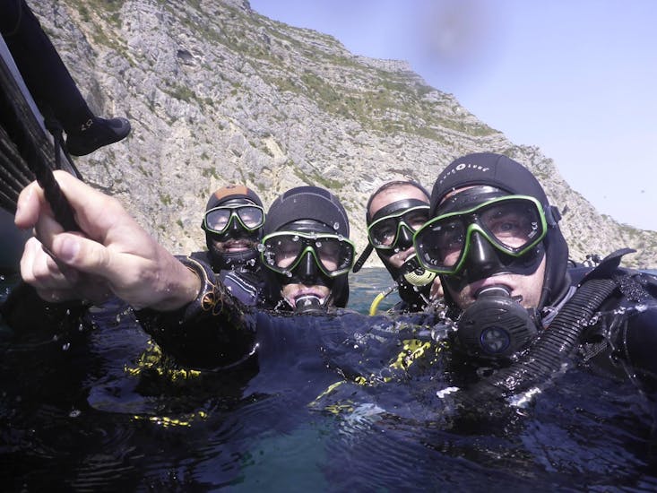 Four friends in the water with scuba gear on a guided boat dive with Haliotis Sesimbra.