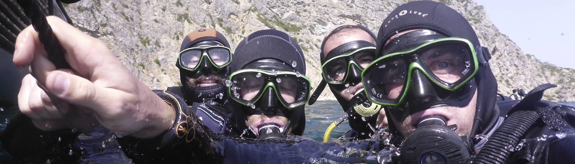 Four friends in the water with scuba gear on a guided boat dive with Haliotis Sesimbra.
