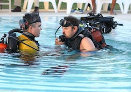 Ein Teilnehmer und ein Guide im geräumigen Pool beim Üben im Scuba Diver Kurs mit Haliotis Sesimbra.