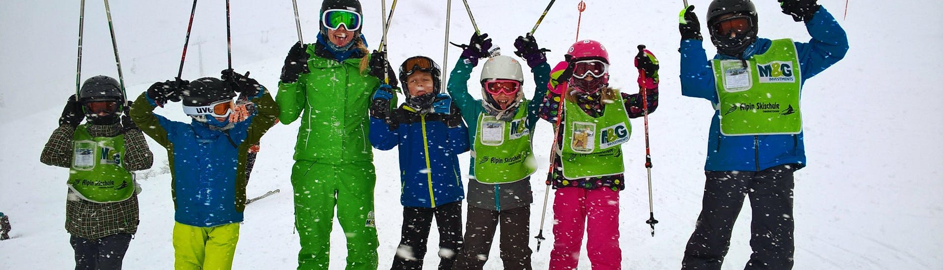 Een groep blije kinderen tijdens de Kids Ski Lessons (9-16 jaar) - Gevorderden met hun skileraar van de skischool Alpin Skischule Oberstdorf.