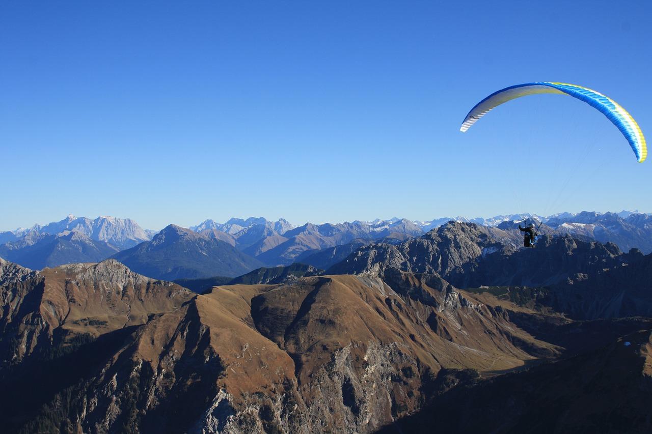 Ein Tandem Paraglider gleitet über die Berge während des Tandem Paragliding von der Jöchelspitze - Thermikflug mit onair Paragliding Center Tirol.