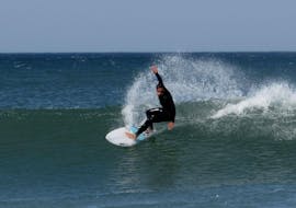 A guy surfing on the waves during Surfing Lessons for Kids & Adults all Levels with Zambeachouse Lourinhã.