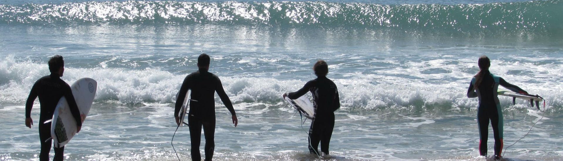 Vier Jungs stehen im Meer während des Surfkurses für Kinder und Erwachsene für alle Niveaus mit Zambeachouse Lourinhã.
