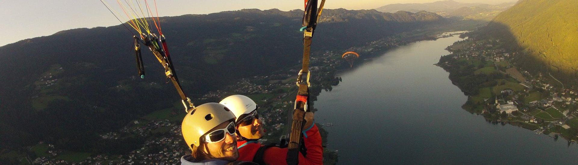 Paragliden boven het meer tijdens zonsondergang tijdens tandem paragliden vanaf Gerlitzen in de avond met Adventure-Wings Ossiachersee