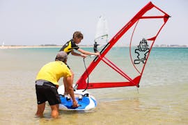 Our instructor is helping a kid with his first steps with the board during the Private Windsurfing Lessons for Kids & Adults - All Levels with KiteSchool.pt Lagos.