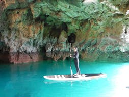 Vista di un uomo durante il suo tour in SUP delle grotte e delle scogliere vicino a Sagres con Algarve SUP tours.