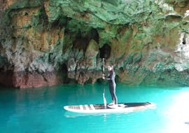 Vista di un uomo durante il suo tour in SUP delle grotte e delle scogliere vicino a Sagres con Algarve SUP tours.
