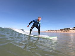 A young man is learning how to surf during the 1-Day Surfing Lessons on Praia da Galé in Albufeira with SUPA Surf School Albufeira.