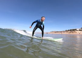 A young man is learning how to surf during the 1-Day Surfing Lessons on Praia da Galé in Albufeira with SUPA Surf School Albufeira.