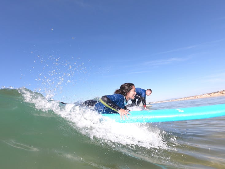 A woman starts surfing on a wave during a 1-Day Surfing Lessons on Praia da Galé in Albufeira with SUPA Surf School Albufeira.