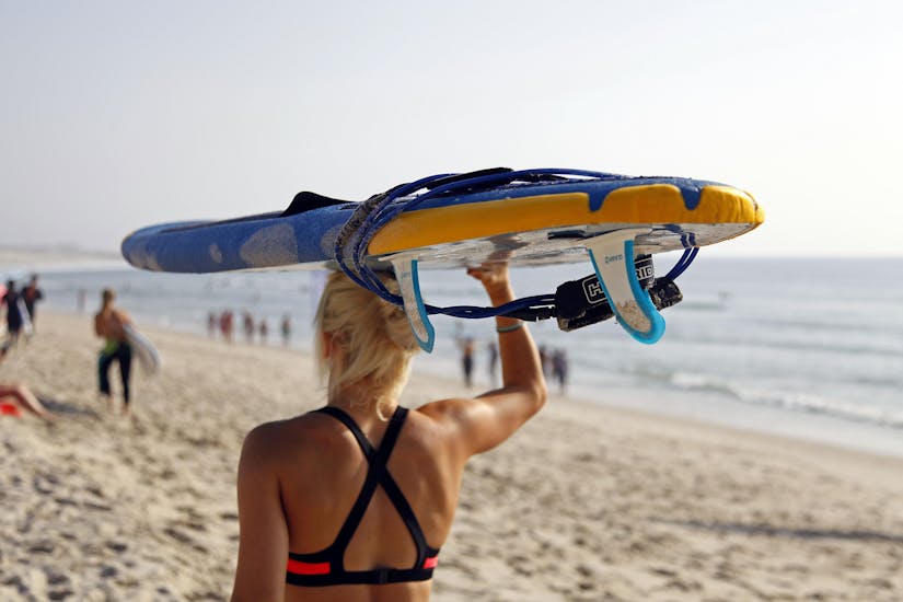 A young girl lifts her board during her Private Surfing Lesson on Praia da Galé in Albufeira with SUPA Surf School Albufeira.