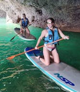 Deux personnes rentrent dans la grotte lors de la Balade guidée en Stand Up Paddle le long de la côte d'Albufeira avec SUPA Sea Adventures Algarve.