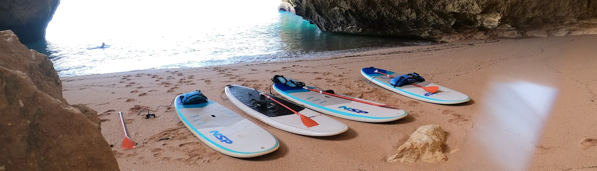 De boards liggen op het zand terwijl we de grotten verkennen tijdens de Stand Up Paddle Tour naar de Benagil Grotten met SUPA Sea Adventures Algarve.