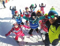 Un groupe de jeunes passionnés de ski s'amuse avec leur moniteur de ski de l'école de ski Prosneige Val d'Isère pendant leur Cours de ski pour Enfants (5-13 ans) - Tous niveaux.