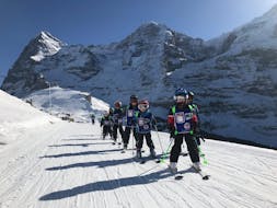 Een groep kinderen vermaakt zich tijdens de Kids Skilessen (vanaf 3 jaar) voor beginners van de Zwitserse Skischool Wengen.