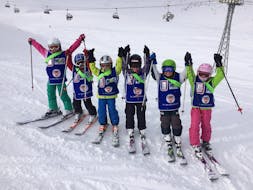 Eine Gruppe von Kindern jubelt beim Kinderskikurs (ab 3 Jahren) für Fortgeschrittene der Schweizer Skischule Wengen.