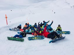 Een groep snowboarders ligt op de piste en juicht bij de snowboardcursus (vanaf 8 jaar) voor beginners met de Zwitserse Skischool Wengen.