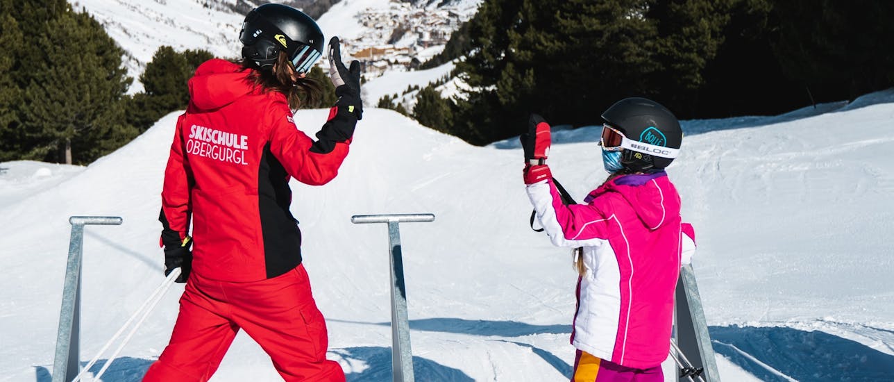 Eine Skilehrerin und ein Kind geben sich ein High Five in einer Privaten Kinder-Skikurs für alle Levels.