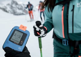 Ein Skitourguide hält ein Gerät in der Hand bei der Skitour für Anfänger mit Skischule Obergurgl.