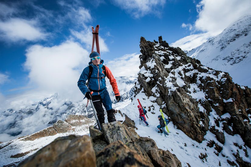 three touring skiers are climbing up the top of a mountain during their ski touring guide for beginners with skischule obergurgl.