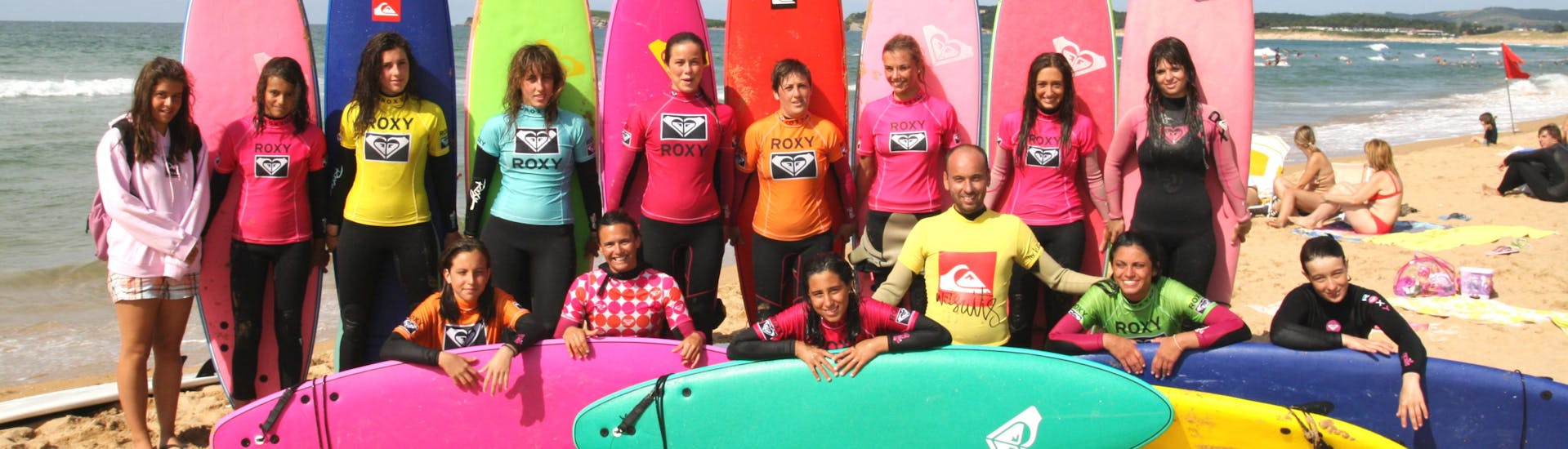 Participante de la lección de surf haciéndose una foto de grupo en la Playa de Somo durante una actividad proporcionada por la Escuela Cántabra de Surf Quiksilver Roxy