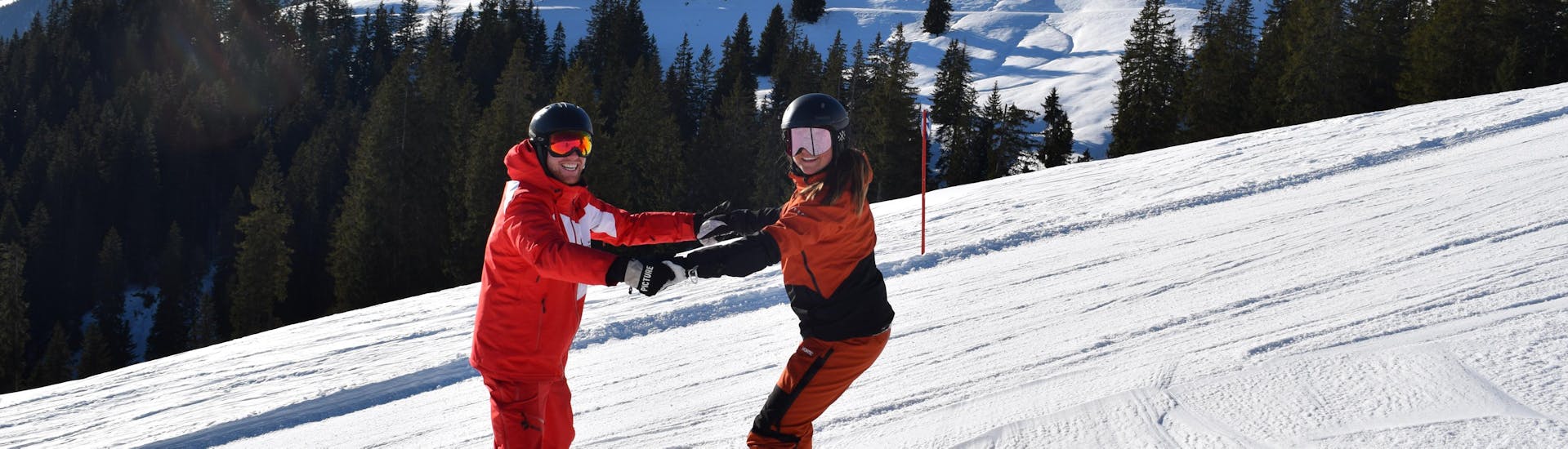 Ein Snowboardlehrer hilft einem Snowboarder beim privaten Snowboardunterricht für Kinder und Erwachsene aller Levels mit der Skischule Snowsports Westendorf.