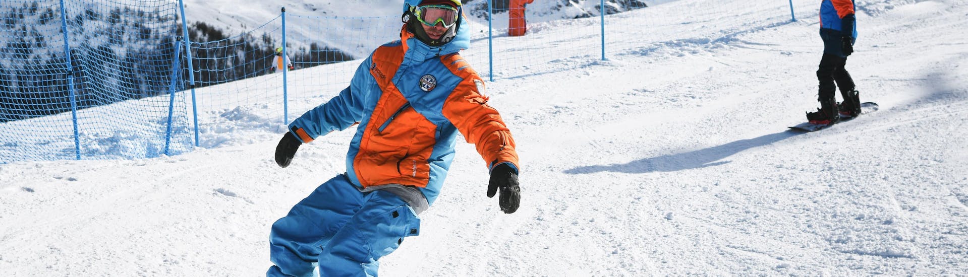 Zwei Snowboarder fahren während der Aktivität Snowboardkurs für Kinder & Erwachsene - Fortgeschritten mit der Skischule YES Academy Sestriere eine beschneite Piste hinunter 