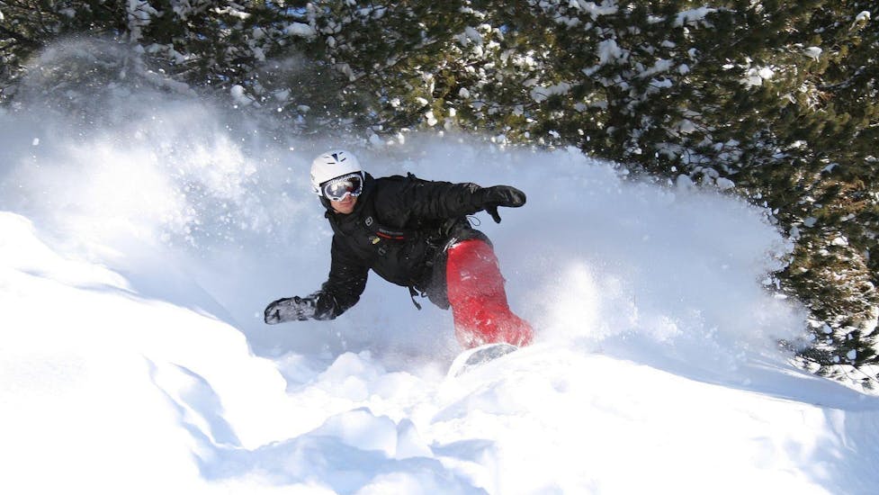 Onder begeleiding van een ervaren instructeur van skischool Skischule Arena in Zell am Ziller rijdt een jonge snowboarder tijdens de privé snowboardlessen voor kinderen en volwassenen - alle niveaus in verse poedersneeuw.