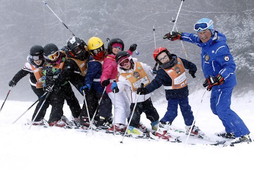 Kinderen vermaken zich met de skileraar in Andalo tijdens een van de Kinderskilessen (6-14 j.) voor Beginners.