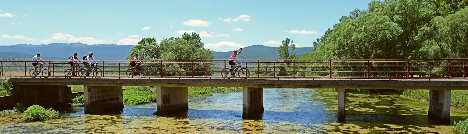 During the Cetina Spring Bike Tour from Sinj, cyclists are crossing a bridge led by a certified guide from Hotel Alkar.