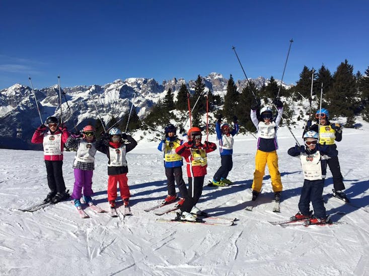 Des enfants avec les mains en l'air à Andalo pendant un des cours de ski pour enfants "Elite" (6-14 ans) pour débutants.